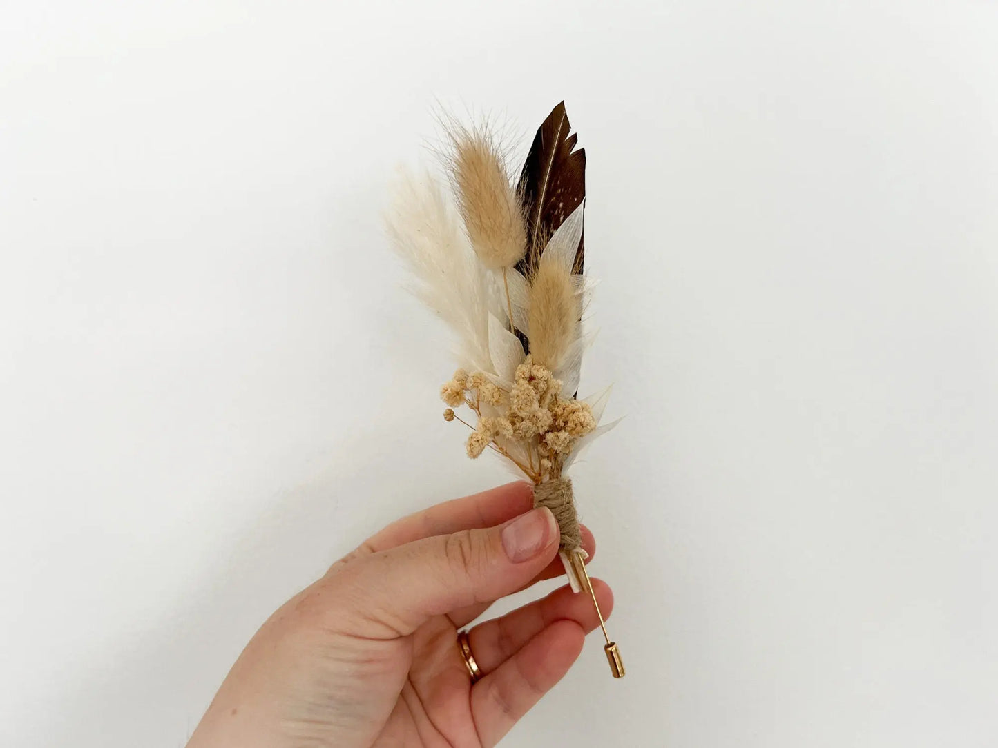 Groom boutonniere with feather and dried wildflowers in boho style