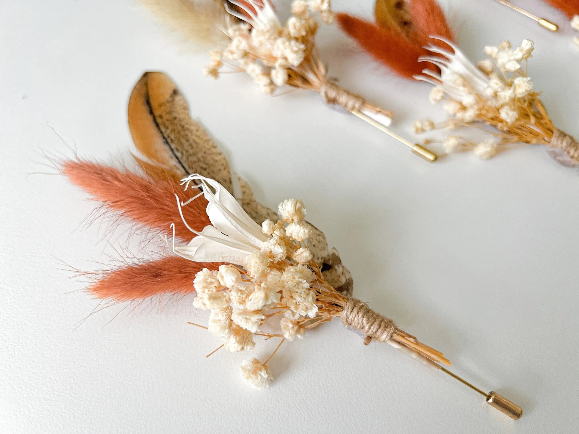 Groom boutonniere with feather and dried wildflowers in boho style